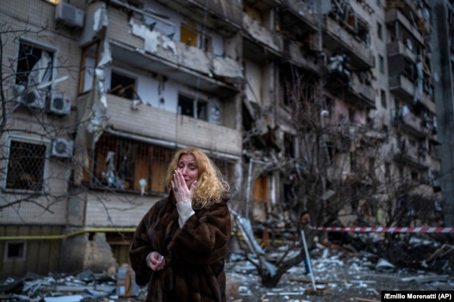 A woman reacts next to her house following a Russian rocket attack on the capital, Kyiv, on February 25, 2022.