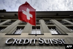 Un steag elvețian este arborat deasupra unui panou al băncii elvețiene Credit Suisse.