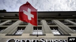  Швейцарский флаг развевается над вывеской швейцарского банка Credit Suisse 8 мая 2014 года в Берне. 