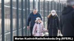 Жінка та її донька проходять через КПВВ у Станиці Луганській, що відокремлює захоплене російськими гібридними силами місто Луганськ від підконтрольної уряду території на сході України. 20 лютого 2022 року
