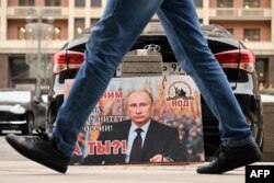 A placard featuring an image of Russian President Vladimir Putin and reading: "We are with him for the sovereignty of Russia! And you?" is seen in front of the Russian State Duma in central Moscow on February 24.