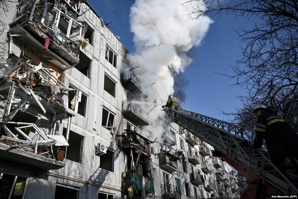 Zjarrfikësit duke shuar zjarrin në një ndërtesë të bombarduar nga forcat ruse në qytetin lindor të Ukrainës, Çuguiv më 24 shkurt 2022.