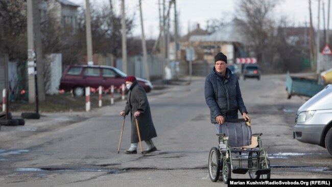 În jurul punctului de control din Luhansk, există mai multe magazine și containere în care oamenii sunt testați de Covid.