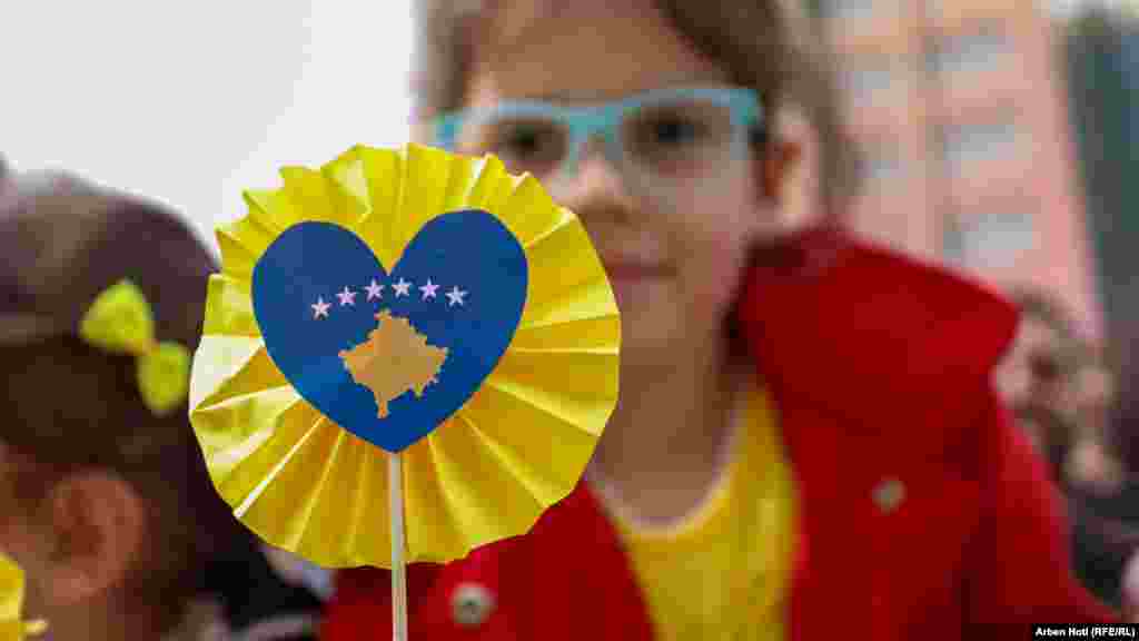 Devojčica sa papirnim ukrasom na kojem je zastava Kosova prisustvuje svečanoj paradi u centru Prištine