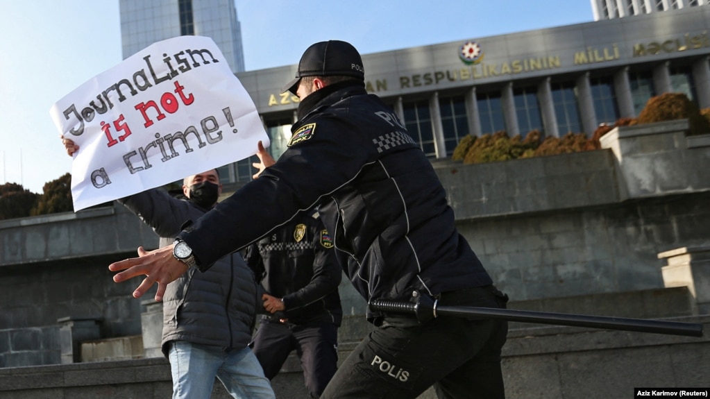 Police officers restrain a protester during a rally of journalists against a new media bill, in front of the parliament building in Baku on December 28. 