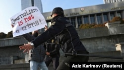 Police officers restrain a protester during a rally of journalists against a new media bill, in front of the parliament building in Baku on December 28. 