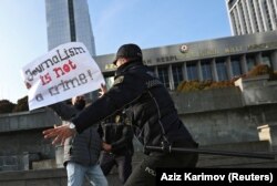 Rendőrök tartanak vissza egy tiltakozót az újságírók új médiatörvény elleni tüntetésén a bakui parlament épülete előtt 2021. december 28-án