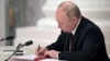 Russian President Vladimir Putin signs documents, including a decree recognizing two Russian-backed separatist formations in eastern Ukraine as independent entities during a ceremony in Moscow on February 21. 
