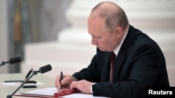 Ruski predsjednik Vladimir Putin potpisuje dokumente, uključujući dekret kojim se dvije otcijepljene regije koje podržava Rusija u istočnoj Ukrajini priznaju kao neovisni entiteti, tokom ceremonije u Moskvi, Rusija, 21. februara 2022.