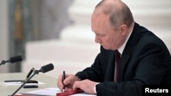 Рускиот претседател Владимир Путин потпишува документи, вклучително и декрет за признавање на две сепаратистички ентитети поддржани од Русија во источна Украина за време на церемонијата во Москва на 21 февруари.