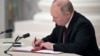 Russian President Vladimir Putin signs a decree recognizing two Russia-backed regions in eastern Ukraine as independent entities during a ceremony in Moscow on February 21.