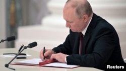 Russian President Vladimir Putin signs a decree recognizing two Russia-backed regions in eastern Ukraine as independent entities during a ceremony in Moscow on February 21.