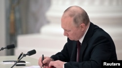 Рускиот претседател Владимир Путин потпиша декрет за признавање на двата региони поддржани од Русија во источна Украина како независни ентитети за време на церемонијата во Москва на 21 февруари.