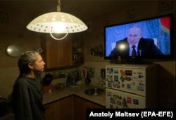Женщина смотрит обращение президента России Путина, где он сообщает о признании самопровозглашенных «ДНР» и «ЛНР»
