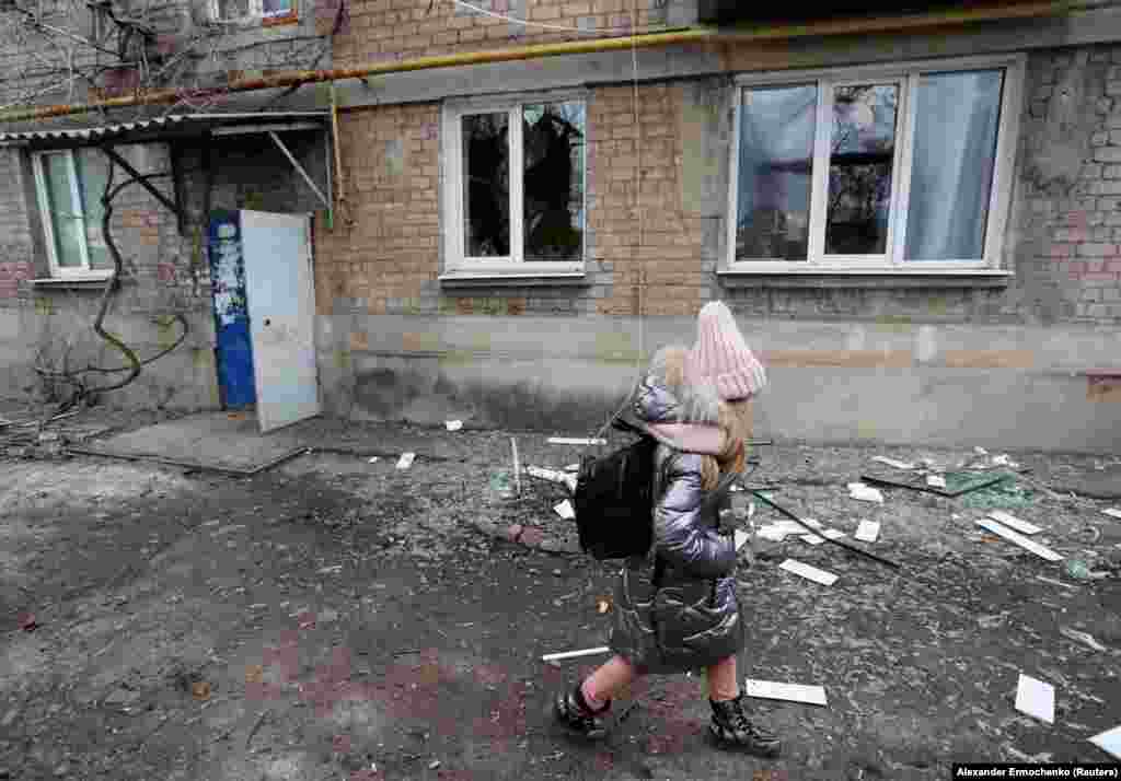 A girl walks past an apartment building, which locals said was damaged by recent shelling, in the separatist-controlled town of Yasynuvata in the Donetsk region.