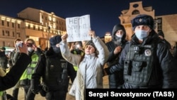 Police detain a demonstrator holding up a sign saying, "No war with Ukraine," during an unsanctioned anti-war protest in Pushkin Square in central Moscow on 24 February.