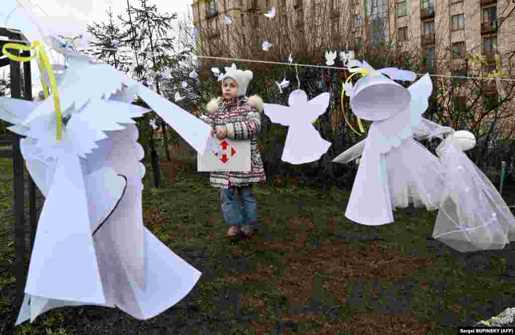 A girl looks at symbolic paper angels paying tribute to the &quot;Heroes of the Heavenly Hundred,&quot; referring to those killed during anti-government demonstrations in early 2014, during a memorial event near Kyiv&#39;s Independence Square, known as the Maidan, on February 18.