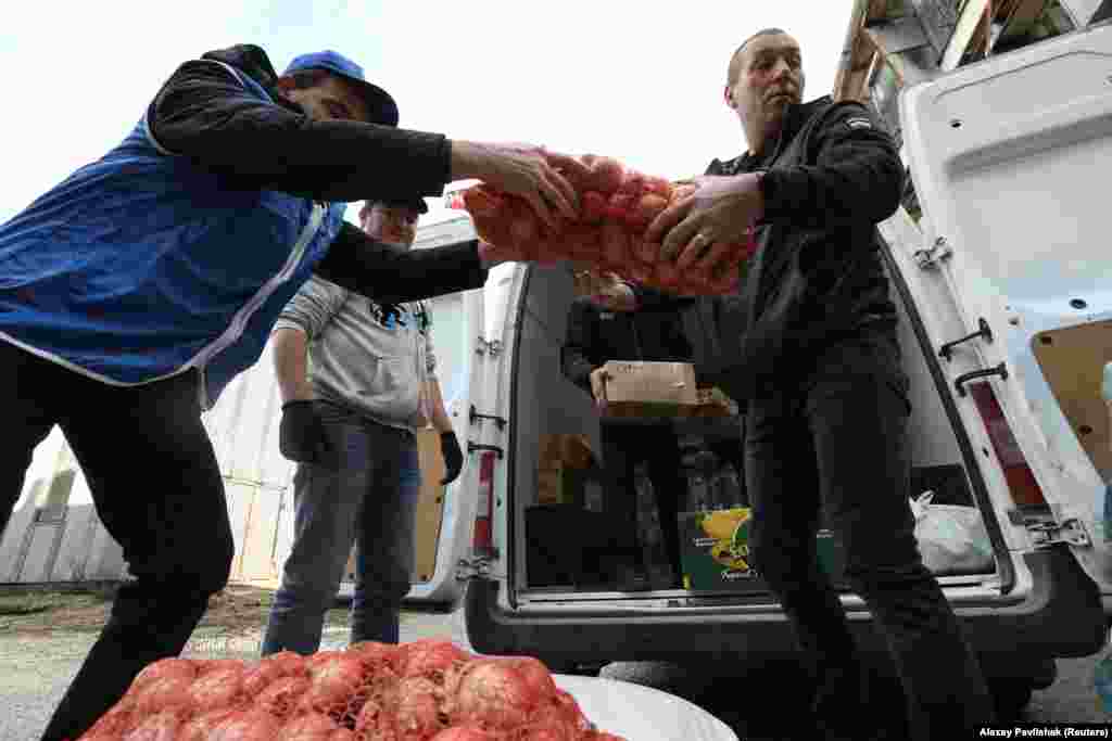 Az evakuáltak számára gyűjtött tartós élelmiszert pakolják be autókba indulás előtt a krími Szimferopolban 2022. február 21-én