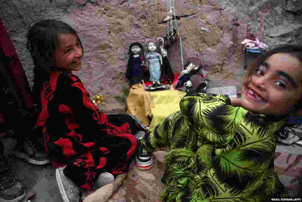 Internally displaced Afghan girls plays with their dolls near their tents at the Shaidayee refugee camp in the Injil district of Herat Province.