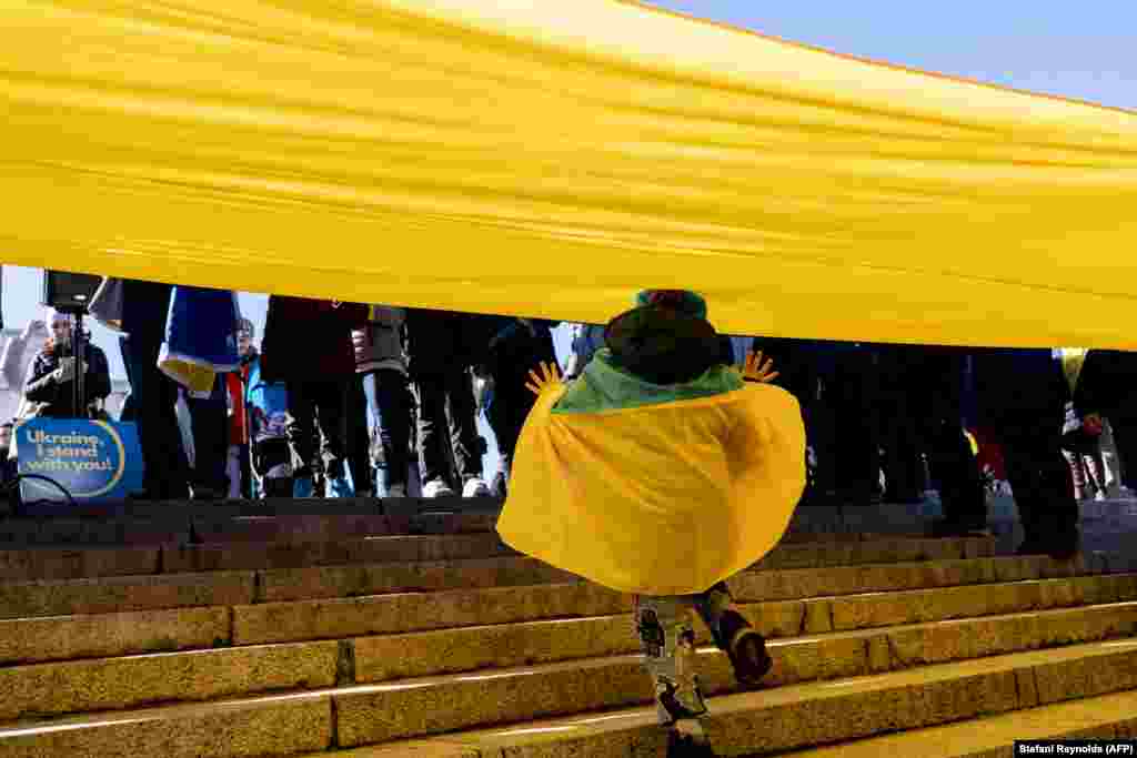 A child runs under the Ukrainian flag as people gather for a Day of Solidarity with Ukraine at the Lincoln Memorial in Washington, D.C., on February 20.