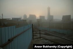 A foggy sunrise behind the skyline of Bukhara’s historic center, seen from a construction site in January 2022.