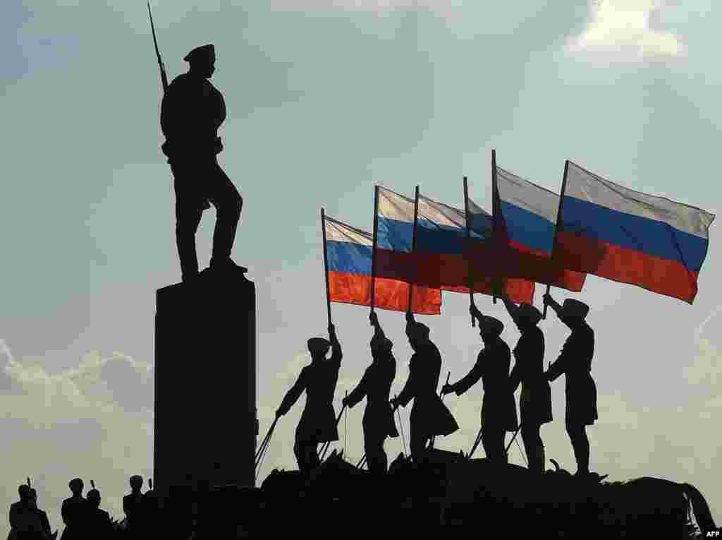 Horseriders hold the Russian national flag next to a bronze statue of a Russian soldier in Moscow during celebrations of the National Flag Day on August 22. (AFP/Vasily Maximov)