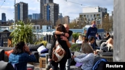 Люди обнимаются в баре на крыше Skylight в связи с ослаблением ограничений в Лондоне. Великобритания, 12 апреля 2021 года.