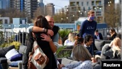 Oamenii se îmbrățișează la un bar rooftop după relaxarea restricțiilor în Londra. REUTERS/Dylan Martinez
