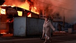 Жінка проходить повз палаючий будинок на місці повітряного удару армії РФ в місті Бровари на Київщині, 14 березня 2026 року 