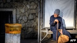 Пожилая женщина сидит на трамвайной остановке. Краснодар, 13 ноября 2017 года