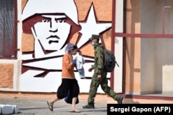 A soldier and a woman walk past the headquarters of Russian troops in the city of Tiraspol, the capital of Moldova's breakaway region of Transdniester. (file photo)