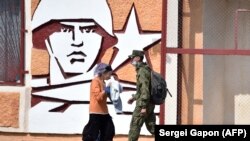Un soldat și o femeie trec prin fața sediului de la Tiraspol al Grupului Operativ de Trupe Ruse