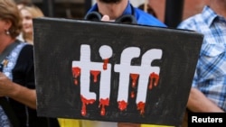 Плакат під час протестів біля Міжнародного кінофестивалю в Торонто (TIFF), де показують документальний фільм «Росіяни на війні» про російські війська, які воюють в Україні, у Торонто, Онтаріо, Канада, 10 вересня 2024 року