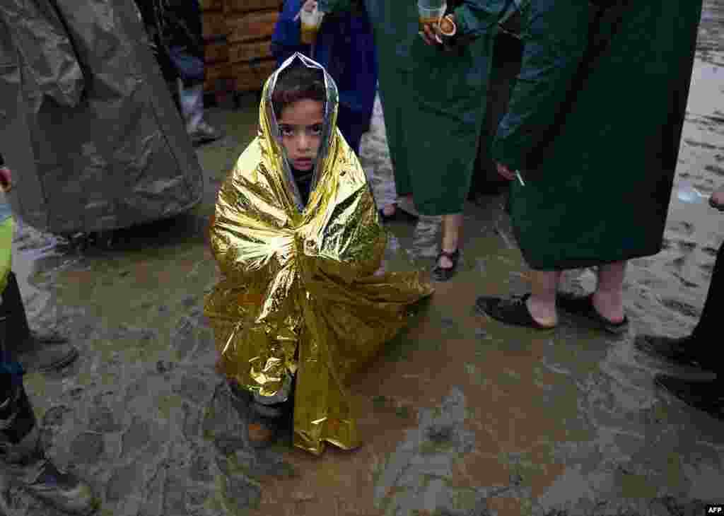 A child wrapped in a survival blanket looks on as migrants queue for hot soup in a makeshift camp at the Greek-Macedonian border, near the Greek village of Idomeni, where thousands of refugees and migrants are stranded by the Balkan border blockade. (AFP/Daniel Mihailescu)