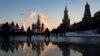 Emberek sétálnak a moszkvai Vörös téren, háttérben a Szpasszkaja toronnyal (jobbra) és a Boldog Vazul-székesegyházzal (középen) 2021. december 28-án