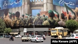 Vehicles travel past a huge banner in Tehran's Revolution Square as a cease-fire appeared to hold.
