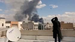 Жена наблюдава черния дим след експлозия в Техеран, Иран, 1 март 2026 г.