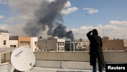 Жена наблюдава черния дим след експлозия в Техеран, Иран, 1 март 2026 г.