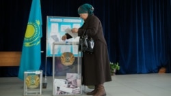 Женщина опускает бюллетень в избирательную урну на участке в Алматы. 20 марта 2016 года.