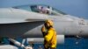 A crew member signals to a pilot in an F/A-18 fighter jet on the deck of the USS Abraham Lincoln aircraft carrier in the Arabian Sea, Monday, June 3, 2019. 