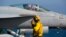 A crew member signals to a pilot in an F/A-18 fighter jet on the deck of the USS Abraham Lincoln aircraft carrier in the Arabian Sea, Monday, June 3, 2019. 