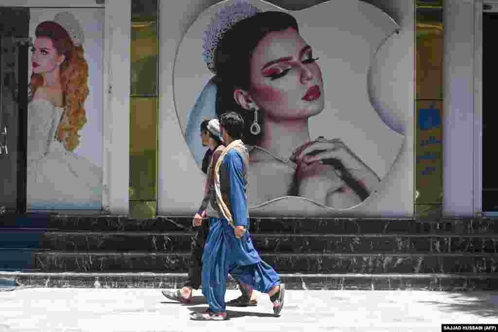 Burra afganë duke ecur para pllakateve të vendosura në objektin e një salloni bukurie, në kryeqytetin e Afganistanit. (7 gusht)