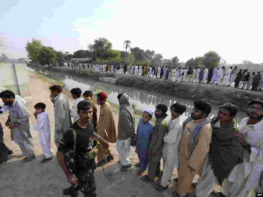 Pakistan -- Internally displaced Pakistani civilians flee from military operations against Taliban militants in South Waziristan, Dera Ismail Khan, 26Oct2009 - PAKISTAN, Dera Ismail Khan : Internally displaced Pakistani civilians, fleeing from military operations against Taliban militants in South Waziristan, wait in line for relief supplies outside a distribution point in Dera Ismail Khan on October 26, 2009. Pakistan launched a three pronged offensive in South Waziristan region near the Afghan border on October 17 and the army says 178 militants and around two dozen troops have been killed since then as some 120,000 people have already fled the army offensive in the South Waziristan.