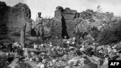 Армяндар геноциді институт-мұражайынан алынған 1915 жылы түсірілген Муш алқабындағы ауылда қырылған армяндардың бас сүйектері жанында тұрған сарбаздар.