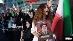 Keçən ay Tehranda keçirilən dövlət mitinqində hicabsız qadın mərhum Ali lider Əli Xameneinin portretini tutur.