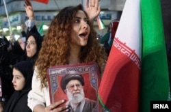 An unveiled woman holding a photo of slain Supreme Leader Ayatollah Ali Khamenei attends a state-sponsored rally in Tehran last month.