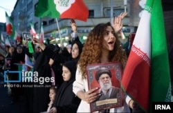 Žena bez marame drži fotografiju ubijenog vrhovnog vođe ajatolaha Alija Hamneija na skupu koji je sponzorisala država u Teheranu, Iran, 18. april 2026.