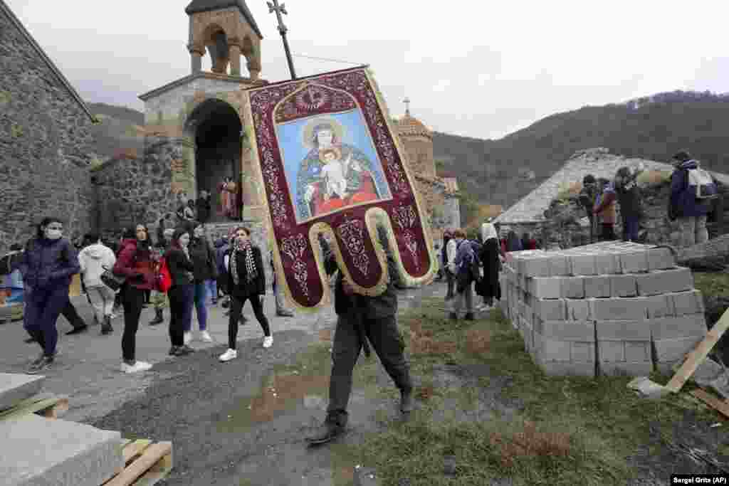 Служитель армянской церкви несет религиозный вымпел из монастыря Дадиванк в Кельбаджарском районе.