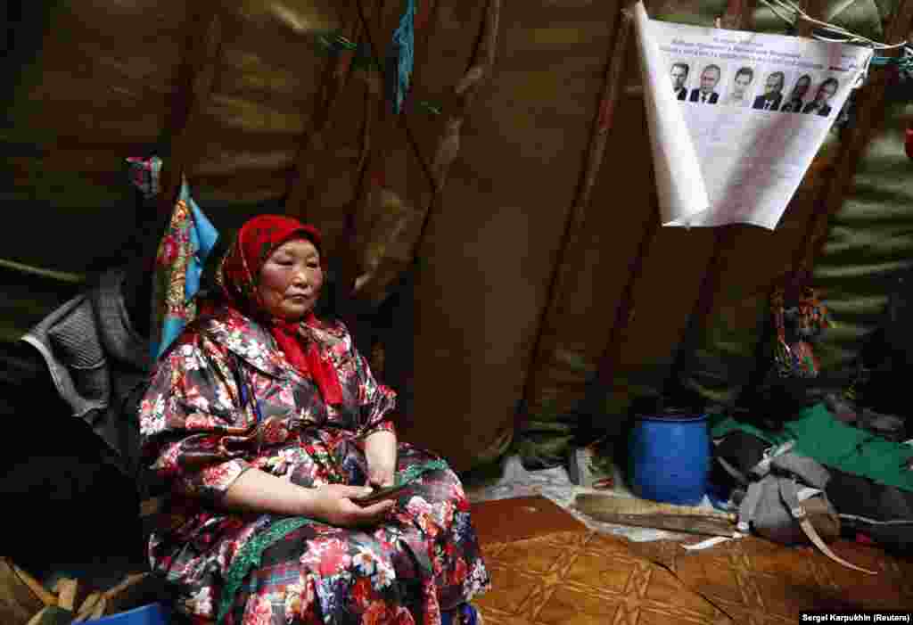 A woman sits under a sheet of paper with information&nbsp;about the presidential candidates, inside a chum - a large tent made of tall wooden poles covered with reindeer hides.