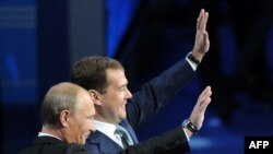 Russian Prime Minister Vladimir Putin (nearer, left) and President Dmitry Medvedev wave to attendees at a United Russia party congress in Moscow on September 24.